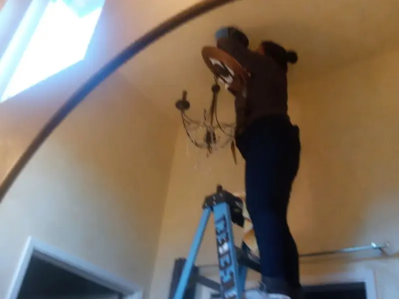 Electrician installing a chandelier in a Sacaton residence